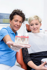 Zahnärztin zeigt einer Patientin das Modell eines Implantates