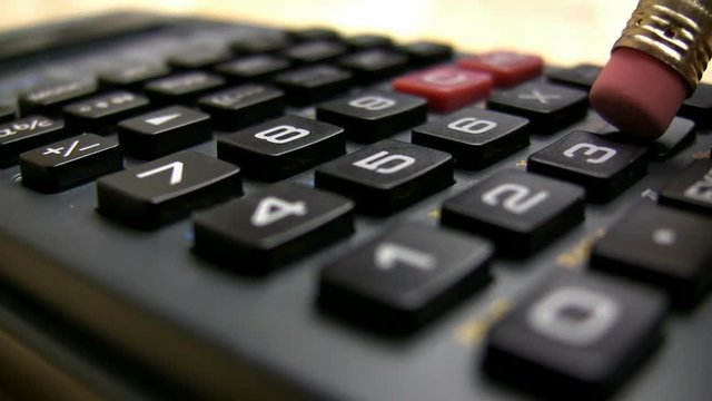 A pencil erase hits the keys on a digital calculator to do a little math.
