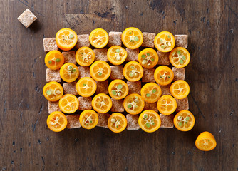 Obraz na płótnie Canvas slices of kumquat with pieces of brown sugar, top view