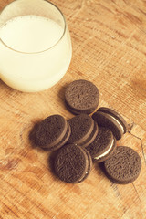 Vaso de leche con galletas de chocolate sobre una mesa de madera rústica. Vista superior