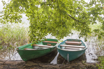 Naklejka na ściany i meble Two fishing boats under green trees in the lake with copy space.