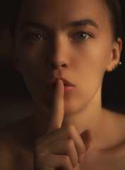Fototapeta premium young beautiful girl holding a finger to her mouth