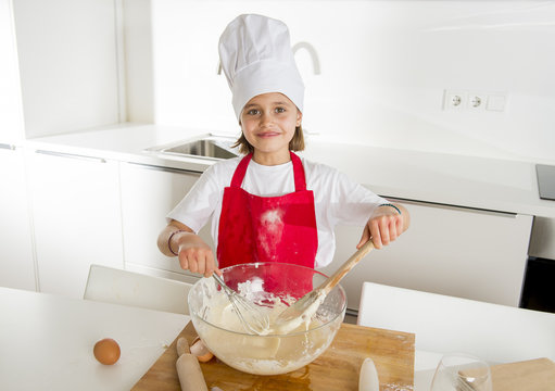mini chef girl with cook hat and apron mixing flour and eggs baking preparing sweet desert smiling happy
