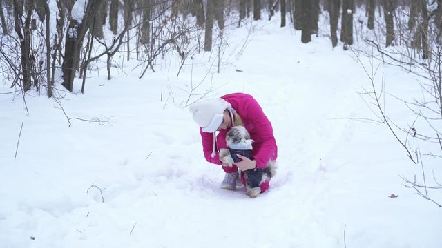 Young blonde woman playing with small dod in winter forest