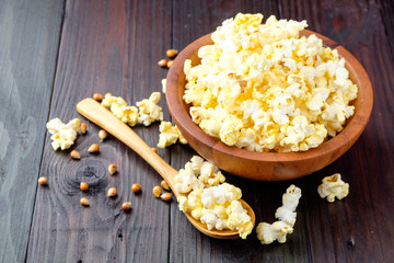 Popcorn in a bowl on wooden background.