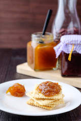 Crackers with orange jam on wooden background