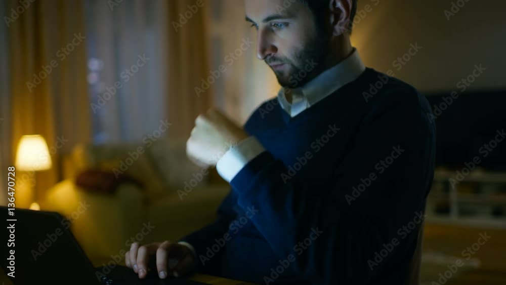 Poster close-up of a respectable middle aged man working on a laptop. he's at home alone. in the background