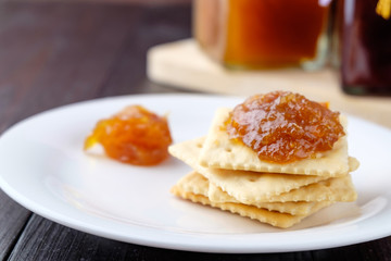 Crackers with orange jam on wooden background