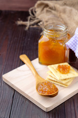 Orange jam on wooden background