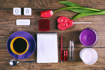 Set of woman accessories Pink Tulip Flower, lollipop, the date block calendar and two cendels on rustic table for March 8, International Womens Day, Birthday, Valentines Day or Mothers day - Top View