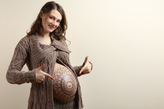 Pregnant woman posing with flower ornament on her belly.
