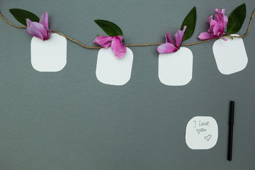 Notes on a rope with flowers on a gray background, space for tex