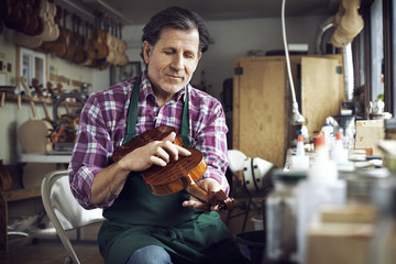 Worker touching violin while working in workshop