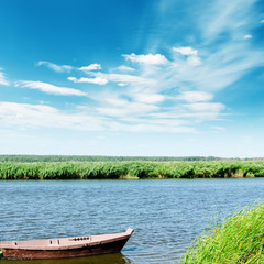 Fototapeta na wymiar river with boat and blue sky with clouds