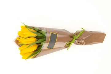 yellow tulips in a paper bouquet tied tape on a white background. Valentine's Day