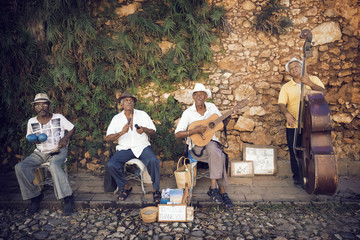 Street musicians playing musical instruments against stone wall