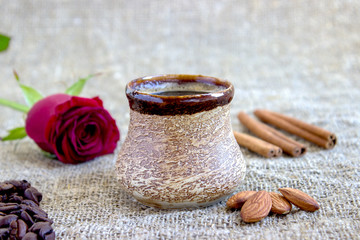 cup of black coffee with coffee beans and cinnamon, red rose