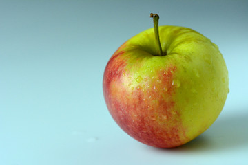 Yellow and red apple covered with drops of water - on a white background