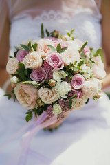 beautiful wedding bouquet of pink and beige spray roses on the hand of the bride close-up