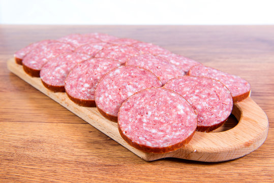 Close-up of chopped smoked sausage on a wooden board.