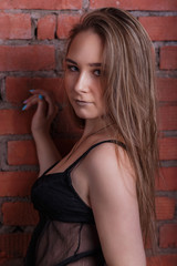Fototapeta premium portrait of beautiful girl blonde with delicate make-up near brick wall looking at the camera in black lingerie