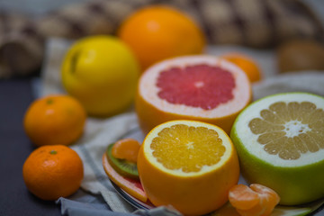 bright juicy citrus fruits in the dish and brown light beige kitchen towel in the kitchen, the festive table closeup