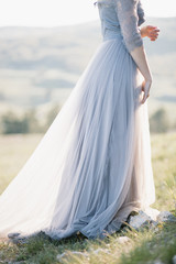 Fototapeta na wymiar girl with beautiful figure in delicate grey blue purple dress made of tulle is on the field