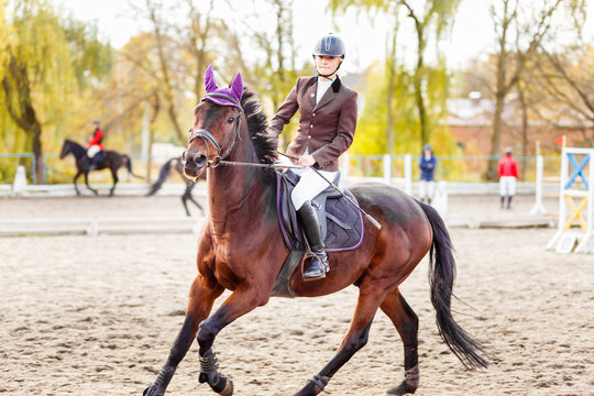 Young jockey girl riding horse on equestrian sport competition