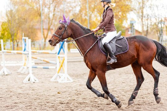 Young jockey girl riding horse on equestrian sport competition