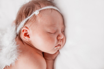 Newborn baby girl sleeping with angel wings.