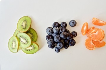 Fruit flower with green kiwi and orange tangerines on the white table