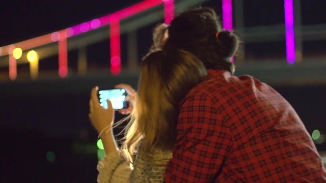 Happy young couple dating, taking picture of beautiful night city on smart phone. Full HD 1080p