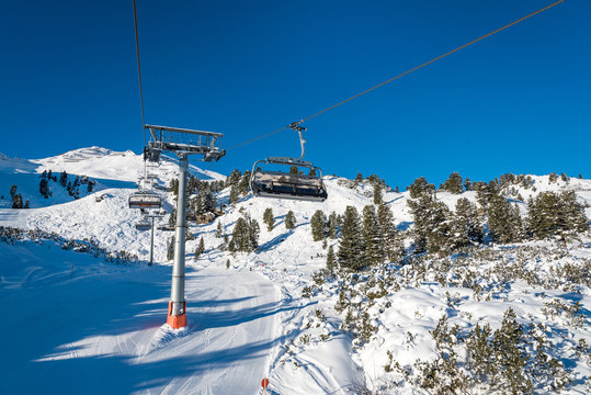 Ski lift with seats going over the mountain and ski tracks