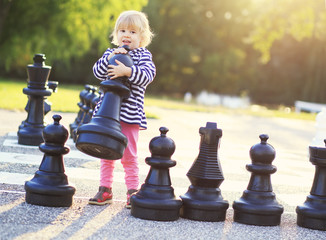 Child with huge chess figures outdoor