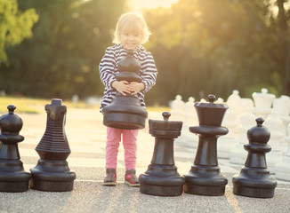 Child with huge chess figures outdoor