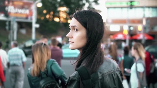 Young beautiful woman standing on the street. Brunette turns and looking to the camera. Slow motion