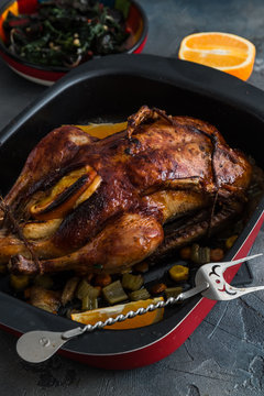 Roast duck and oranges on a black slate board, close view