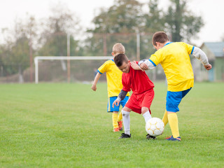 Obraz premium Soccer kid in the battle for the ball against two rival players