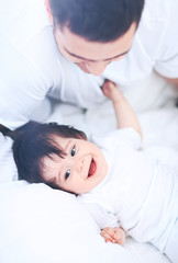 Baby boy lying on bed, next to his father