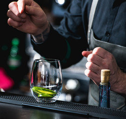 bartender making refreshing coctail with cucumber isolated on a bar background