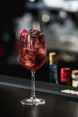 relaxing alcoholic pink coctail with a rose on top isolated on a bar background