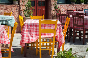 Orange wooden chairs and tables with purple tablecloths in traditional Greek tavern on Santorini island, Greece