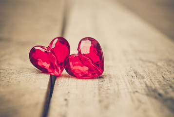 Love for Valentine's day: Two red beads with a shape of a heart on wood plank floor