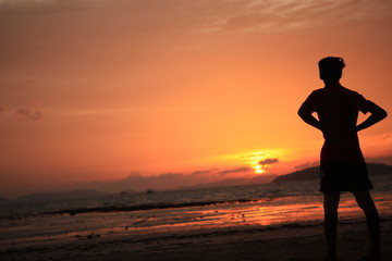 sagoma uomo guarda il tramonto sulla spiaggia 