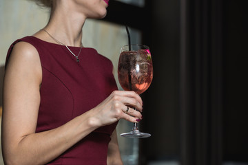 woman holds relaxing alcoholic pink coctail with a rose on top
