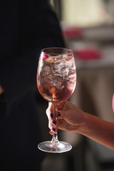 woman holds relaxing alcoholic pink coctail with a rose on top