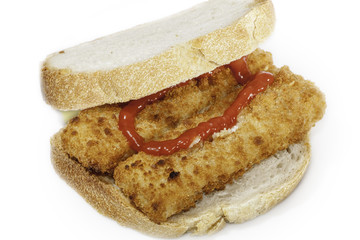 Fishfinger Sandwich. Comfort food as lunch, supper, or as a snack, served with a dollop of ketchup. Pictured against white background.