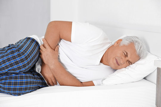 Senior gentleman suffering from pain in bedroom