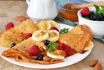 Homemade pancakes with banana, berries and honey for breakfast.