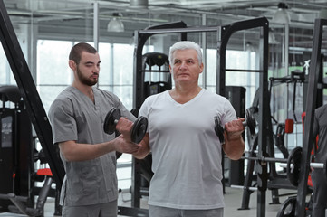 Fototapeta na wymiar Rehabilitation concept. Mature man doing exercises under physiotherapist supervision